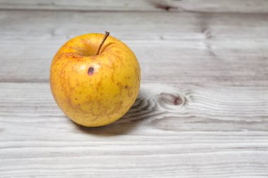 Yalnız sarı sonbahar elması meyvesi, ahşap bir arka planda hala izole bir şekilde duruyor.