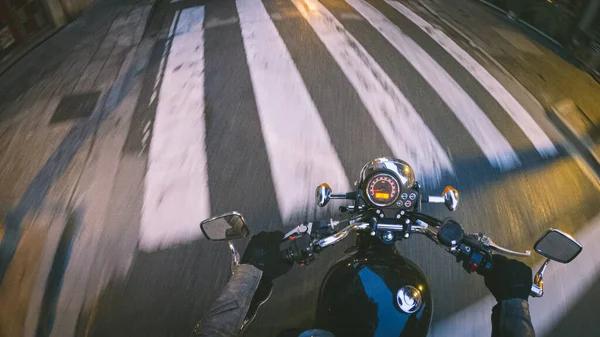 夕暮れ時のドライバーの視点で都市部の道路上で古いヴィンテージの黒いバイクに乗る — ストック写真