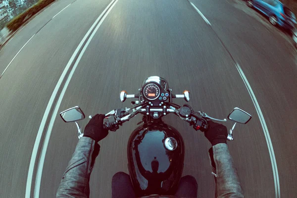 Asfalt yolda hız göstergesi olan eski siyah bir motosiklete binmek.