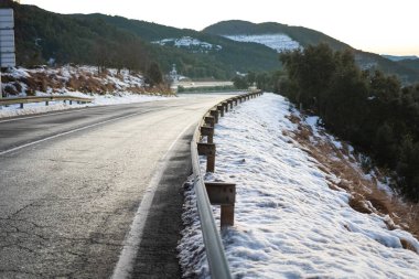 Bir dağ manzarasında, asfalt yolun kenarında kar ve buz.