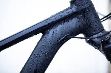 Koyu gri bisiklet çerçevesini yıkayan su damlaları