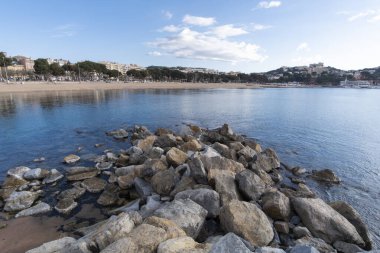 Kumlu bir kumsalın sahilinde kayalar.