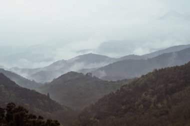 Tepenin tepesinden bulutlu ve sisli dağ manzarası