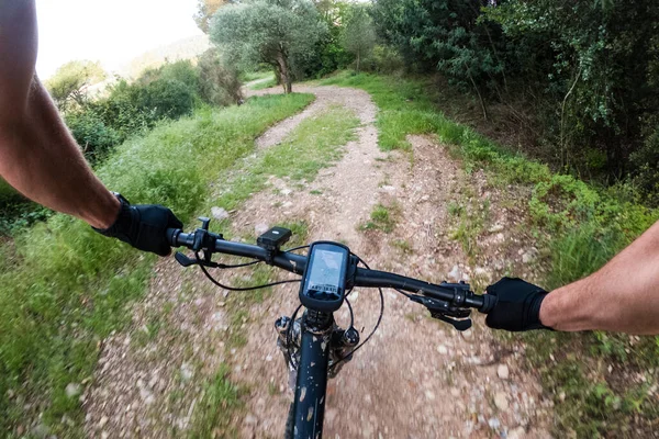 Riding a black mountain bike with nav on a gravel mountain road from a rider chest point of view