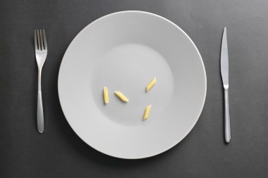 Gri bir boş tabak üzerinde dört penne
