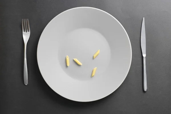 Gri bir boş tabak üzerinde dört penne