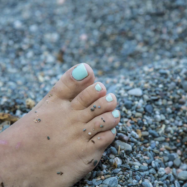 Türkisfarbene Nägel einer Frau am Sandstrand — Stockfoto