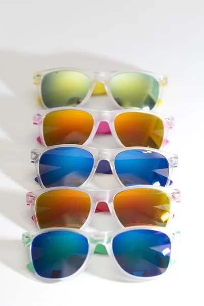 Beyaz bir arka plan üzerinde izole üst üste birçok farklı renkli Güneş gözlükleri — Stok fotoğraf