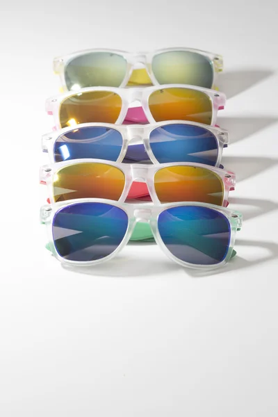 Veel verschillende kleurrijke zonnebril in een rij geïsoleerd op een witte achtergrond — Stockfoto