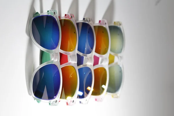 Veel verschillende kleurrijke zonnebril in een rij geïsoleerd op een witte achtergrond — Stockfoto