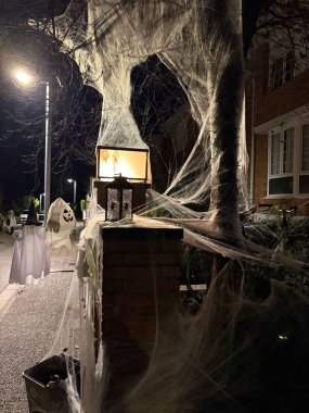 Bir sokak sahnesinde cadılar bayramı kostümü ve örümcek ağlarıyla süslenmiş ön cephe evi.