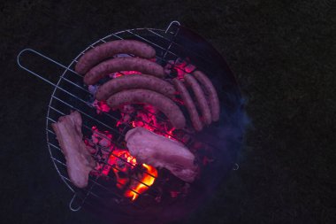 Geceleri ızgara kömür mangalında sosis ve et pişirmek.