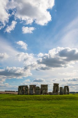 İngiltere 'nin Cotswolds şehrindeki ünlü tarihi Stonehenge yeşil çimenlerin ve görkemli bulutlu gökyüzünün üzerinde