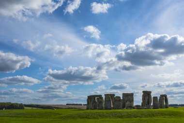 İngiltere 'nin Cotswolds şehrindeki ünlü tarihi Stonehenge yeşil çimenlerin ve görkemli bulutlu gökyüzünün üzerinde