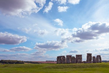 İngiltere 'nin Cotswolds şehrindeki ünlü tarihi Stonehenge yeşil çimenlerin ve görkemli bulutlu gökyüzünün üzerinde