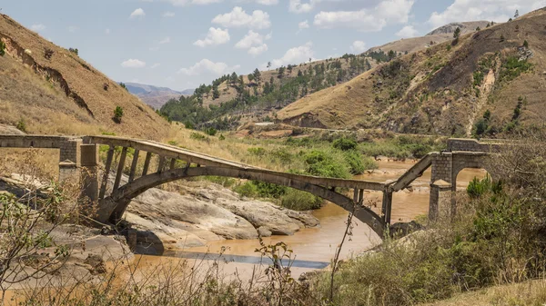 Ponte quebrada velha em um rio lamacento — Fotografia de Stock