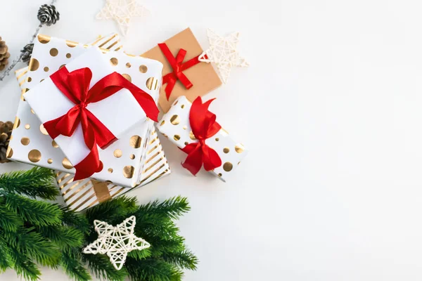 Kırmızı kurdeleli beyaz ve altın renkli hediye kutuları ve noel ağacı dalları ve arka planda fotokopi alanı olan bir yıldız. Üst manzara, düz yatış. Xmas dekorasyonu, şenlikli arkaplan.
