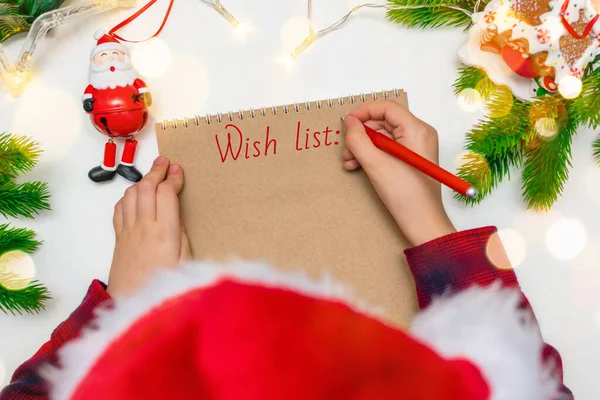 Little Boy Red Christmas Hat Holds Pen His Hand Writes — Stock Photo, Image