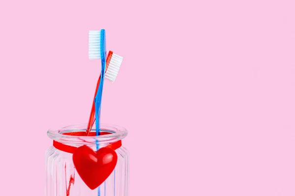 Kırmızılı Bir Bardakta Iki Diş Fırçası Fırça Adam Kadın Kucaklaşması — Stok fotoğraf