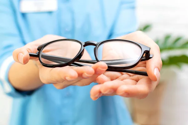 Kobieta Lekarz Okulista Niebieskim Mundurze Trzyma Rękach Daje Parę Okularów — Zdjęcie stockowe