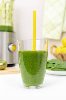 Ev yapımı yeşil ıspanak püresi. Elmalı ve kivili. Mutfak masasının üzerinde pipet içerek. Organik sebze ve meyve suyu. Sağlıklı beslenme ve zayıflatma.