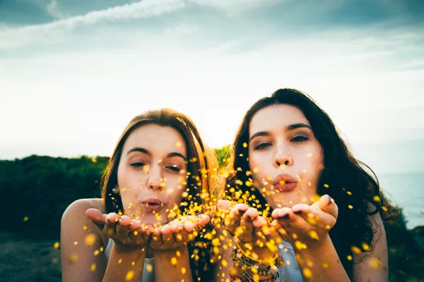 Meninas engraçadas soprando brilho dourado sobre um penhasco — Fotografia de Stock