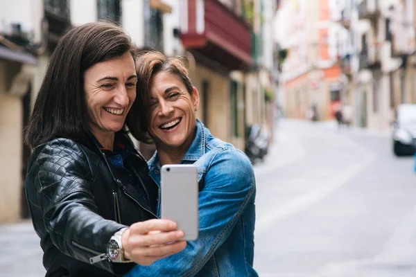 快乐的中年女同性恋夫妇带着智能手机自拍 — 图库照片