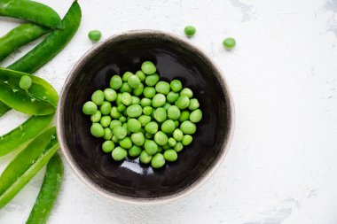 Beyaz kabuklu siyah kase ve taze bezelye kabukları