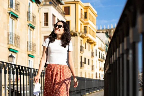 夏にスペインのドノスティアの旧市街を訪れるサングラスを持つ若い幸せな観光客の女性 — ストック写真