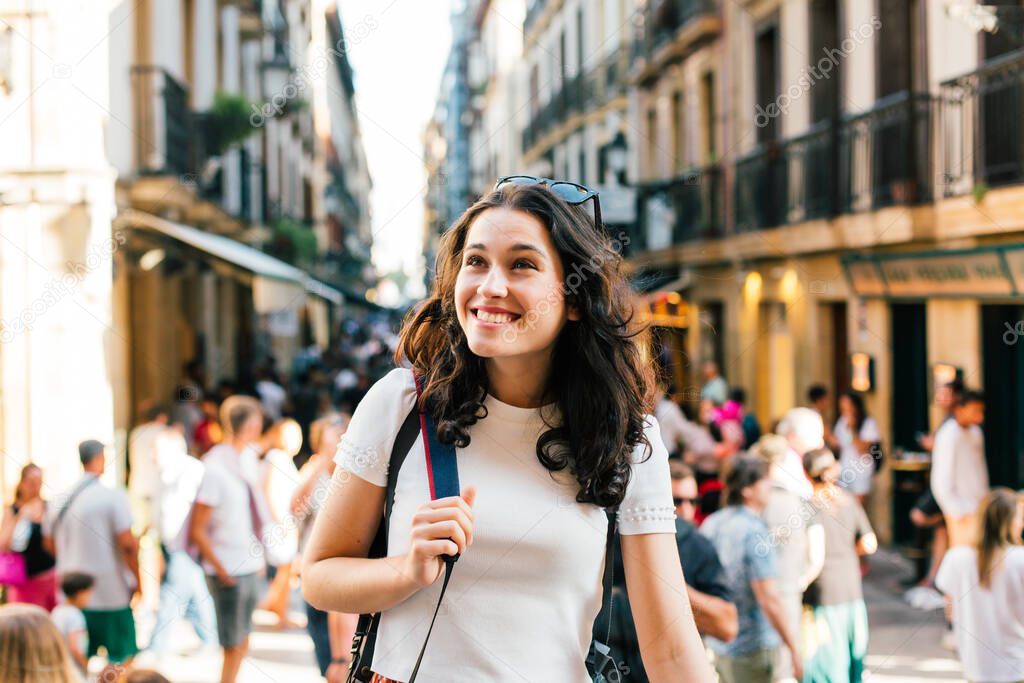 Happy young tourist woman visiting the lively Old Town of San Sebastian, Spain, in summer