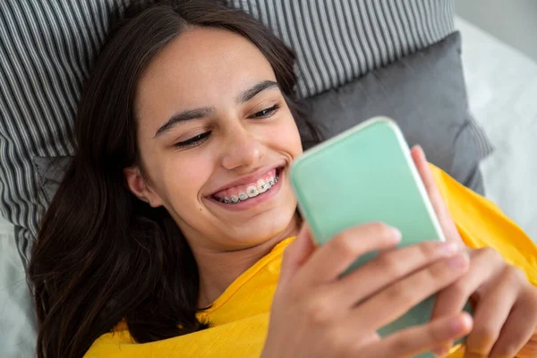 Feliz Adolescente Con Aparatos Ortopédicos Usando Teléfono Inteligente Acostado Cama —  Fotos de Stock