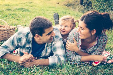 Sonbaharda çimenlerde yatan mutlu üç kişilik bir aile.