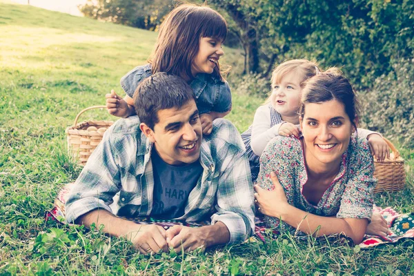 Счастливая семья из четырех человек лежит в траве осенью — стоковое фото