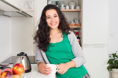 Güzel genç kadın mutfağında bir çay içiyor