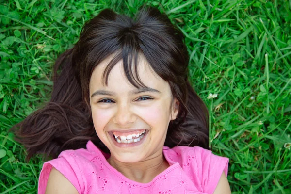 Lustiges Mädchen liegt lachend im Gras — Stockfoto