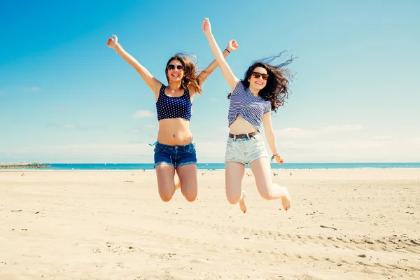 Grappig meisje vrienden springen op het strand — Stockfoto