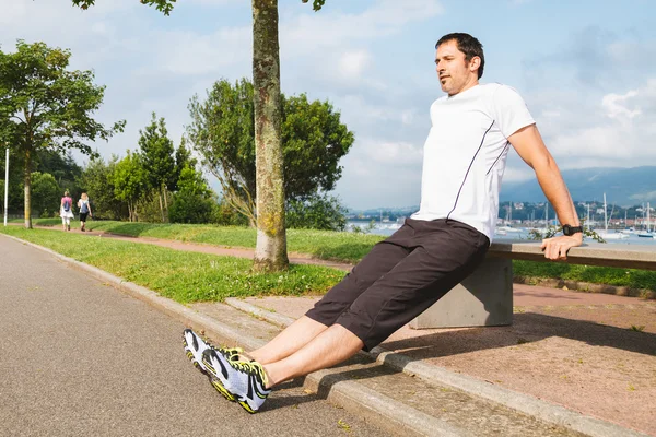 Hombre haciendo flexiones al aire libre usando un banco —  Fotos de Stock