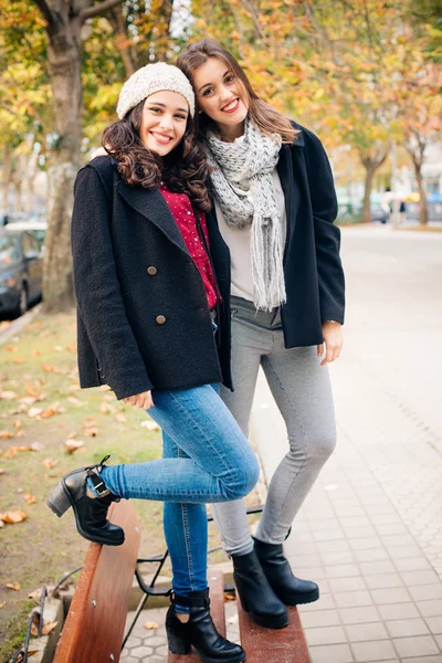 Симпатичные подружки, стоящие на скамейке и улыбающиеся — стоковое фото