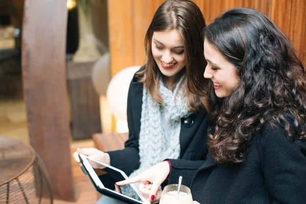 Mulheres jovens usando um tablet em um café — Fotografia de Stock