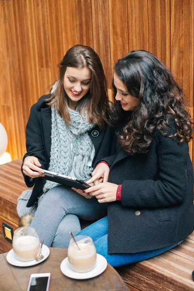 Mulheres jovens usando um tablet em um café — Fotografia de Stock