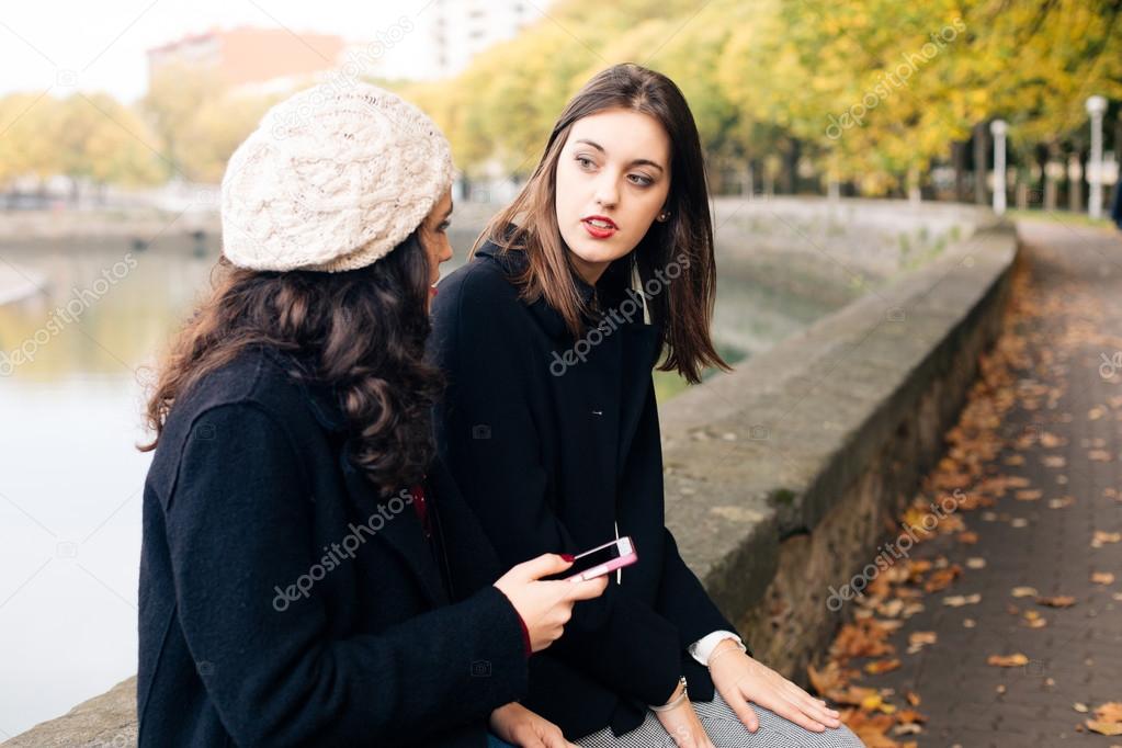 Young women gossiping outdoors