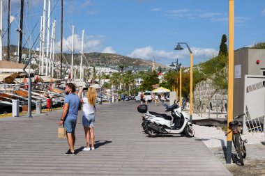 Hindi, Bodrum, Ekim 2020. Bir kız ve bir adam, güneşli bir günde Türkiye 'nin Bodrum kentindeki yatların fotoğraflarını çekiyorlar..