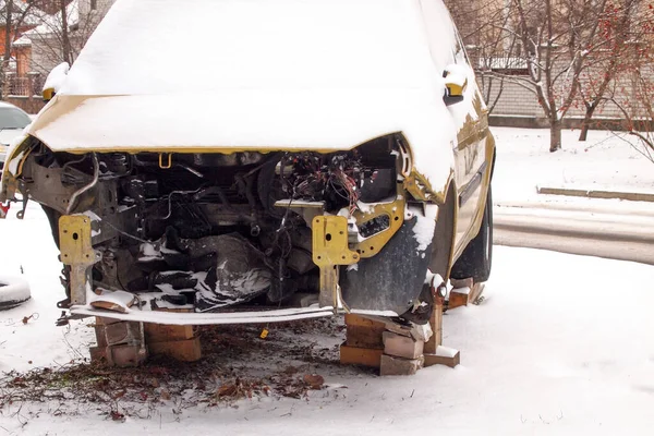 Broken car after an accident under the snow. Consequences of violation of traffic rules.