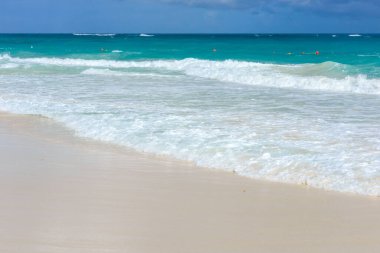 Kumsalda köpüklü bir dalga var. Deniz turkuaz okyanus ve kumlu kıyılar mavi gökyüzüne karşı. Deniz kenarında dinlen. Egzotik ada.