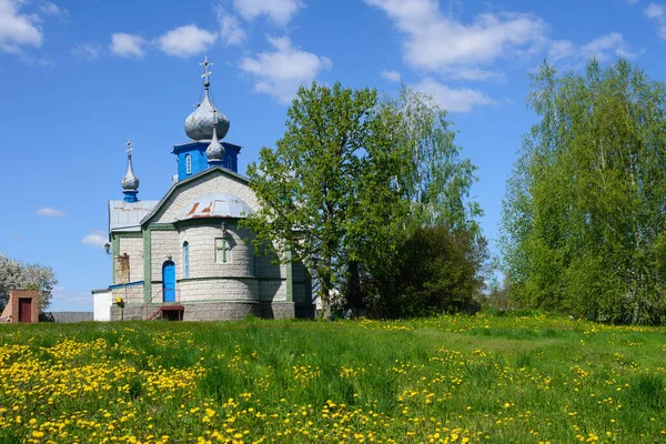 Rural church on a background of blue sky and among dandelions on a warm spring day. Travel by Ukraine.