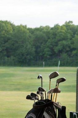 Ukrayna, Harkiv, Haziran 2021. Golf sopaları golf kulübündeki yeşil çimlerin arkasında bir çantada..