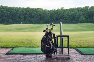 Ukrayna, Harkiv, Haziran 2021. Golf sopaları golf kulübündeki yeşil çimlerin arkasında bir çantada..