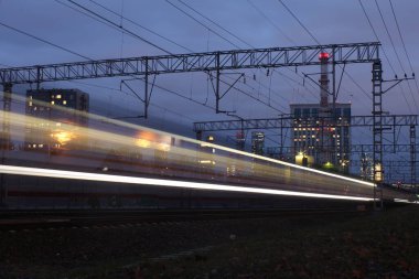 Gece tramvayı rayları, uzun pozlu fotoğraflar, arka plandaki tren ışıkları koyu mavi.