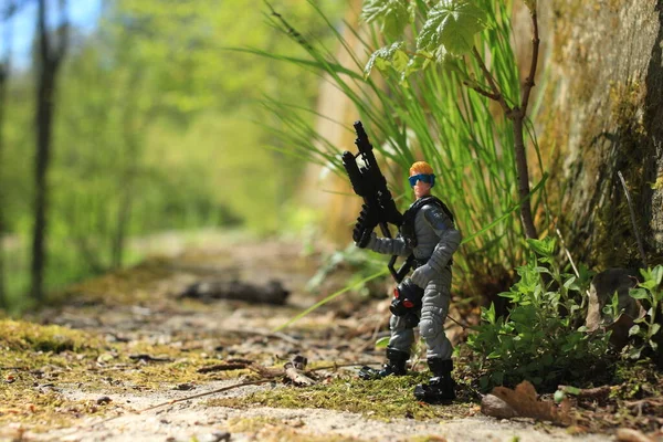 A toy figure of a military soldier with a machine gun in his hands in the green strip of the tropics