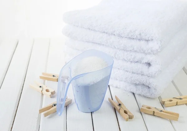 Bath towels, washing powder in measuring cup and wooden clothesp